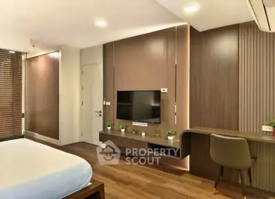 Modern bedroom with sleek wooden paneling and built-in TV, featuring a cozy workspace and stylish decor.