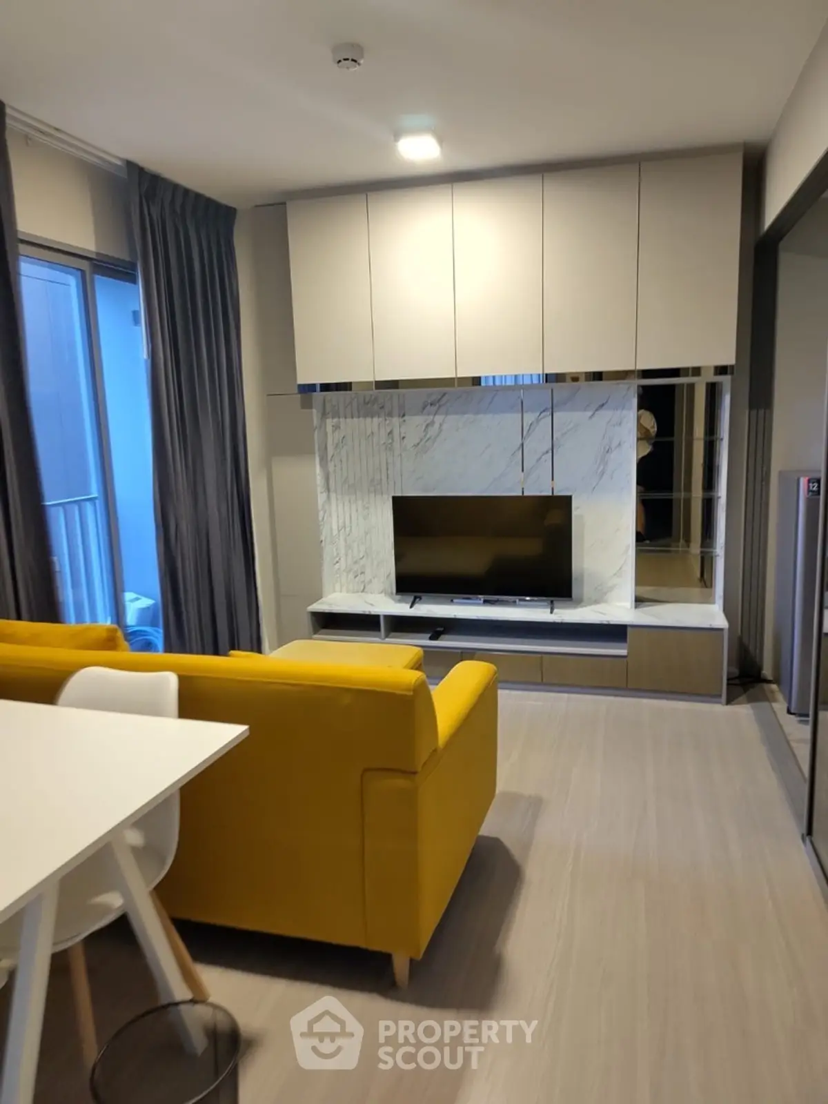 Modern living room with yellow sofa and sleek TV unit, perfect for stylish urban living.