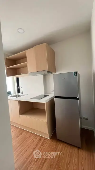Modern kitchen with sleek cabinetry and stainless steel fridge in a compact layout.