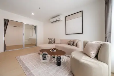 Modern living room with stylish furniture and neutral tones, featuring a cozy sofa and elegant decor.