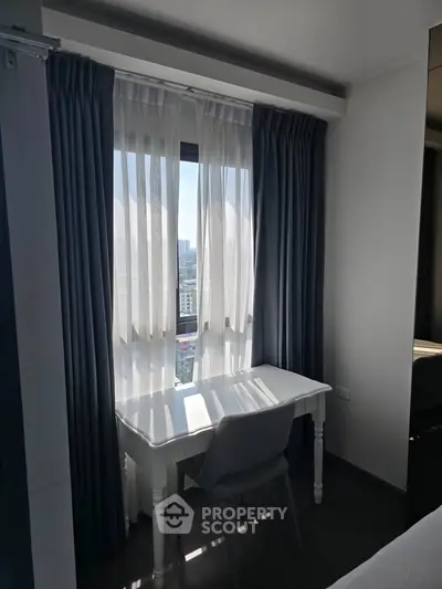 Cozy study nook with a city view, featuring a sleek white desk and comfortable chair by the window.