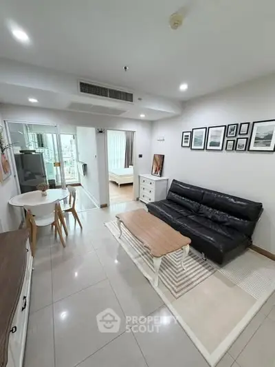 Modern living room with sleek black sofa, stylish decor, and open view to bedroom, perfect for urban living.