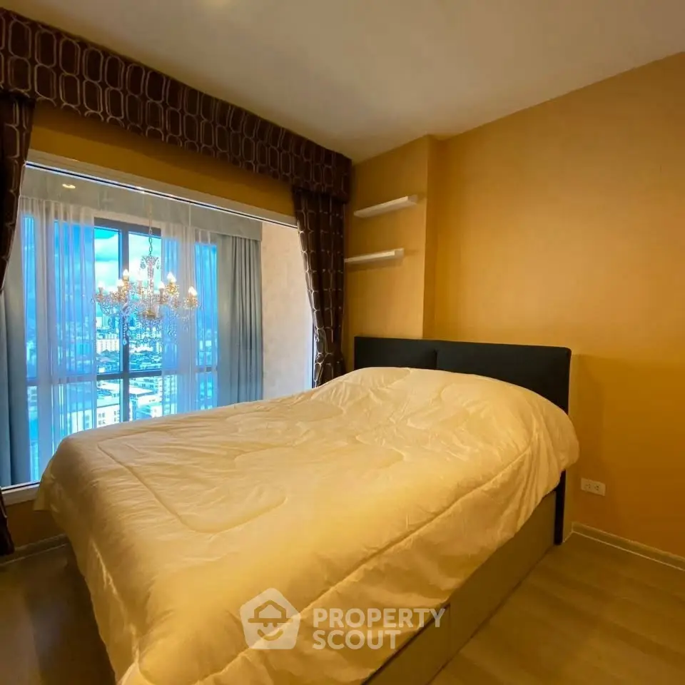 Cozy bedroom with large window and elegant chandelier in modern apartment.