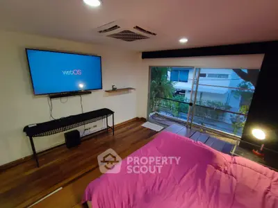 Cozy bedroom with modern TV and large window overlooking greenery.