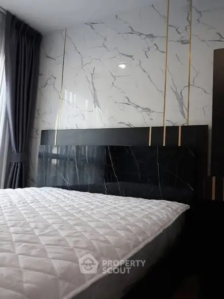 Luxurious bedroom with marble accent wall and elegant bedding in modern apartment.