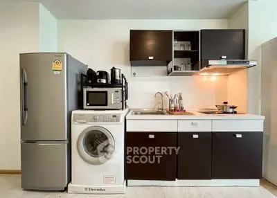 Modern kitchen with appliances including fridge, washing machine, and microwave in sleek design.