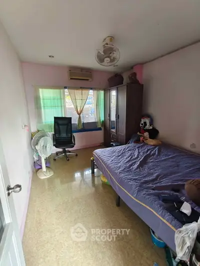 Cozy bedroom with natural light, featuring a comfortable bed, wardrobe, and office chair, ideal for relaxation and work.