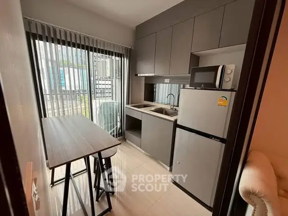 Modern compact kitchen with sleek cabinetry and dining area in urban apartment.