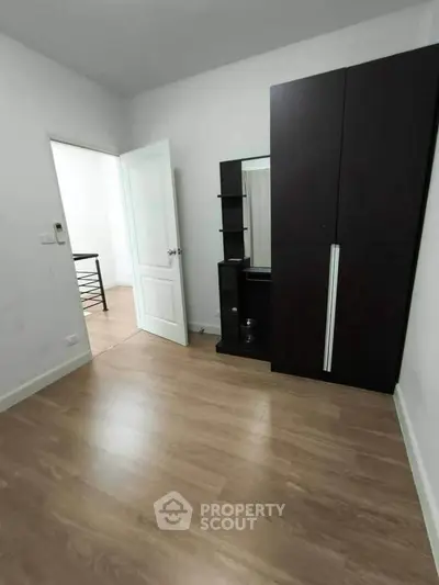 Spacious bedroom with wooden flooring and modern wardrobe in a minimalist design.