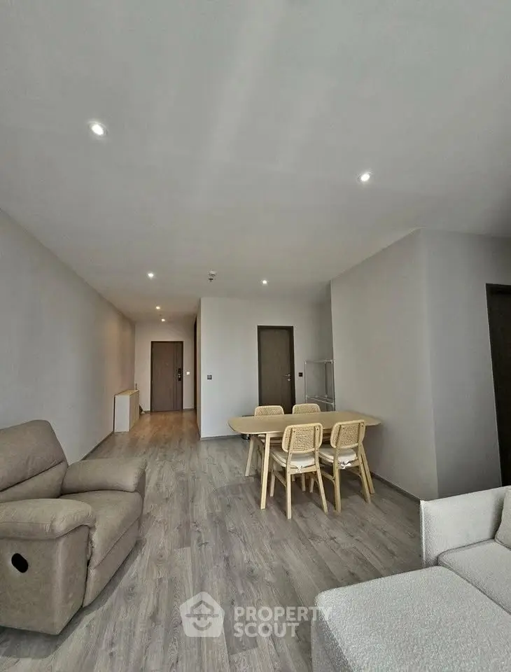 Spacious modern living room with wooden flooring and cozy furniture in a contemporary apartment.