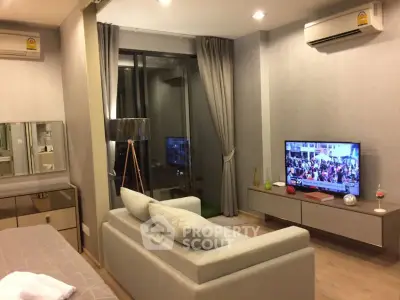 Modern living room with stylish decor and large window view, featuring a cozy sofa and flat-screen TV.