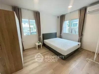 Spacious bedroom with large windows and modern furnishings in a bright, airy home.