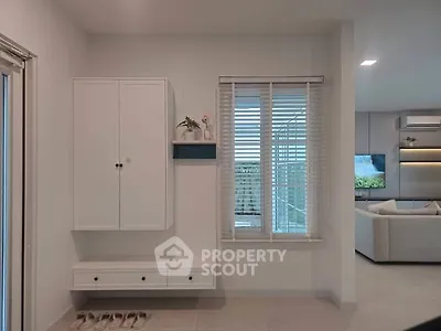 Modern living room with sleek white cabinetry and large window, showcasing a stylish and minimalist design.