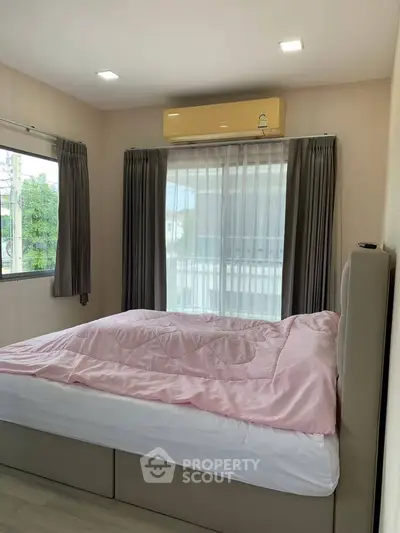 Cozy bedroom with large windows and air conditioning, perfect for relaxation and comfort.