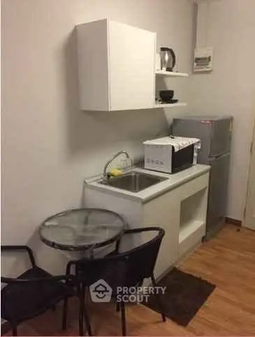 Compact kitchen with modern appliances and small dining area in cozy apartment.