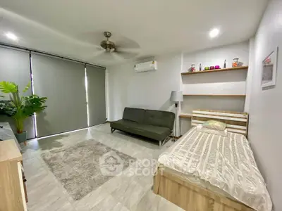 Spacious bedroom with modern decor, featuring a cozy bed, stylish sofa, and elegant lighting.