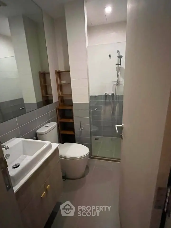 Modern bathroom with sleek design, featuring a glass shower enclosure and contemporary fixtures.