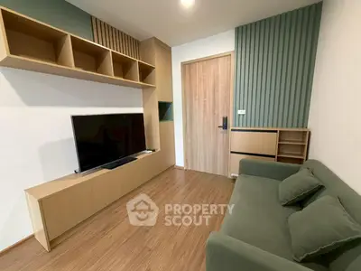 Modern living room with sleek wooden flooring, stylish TV unit, and comfortable green sofa.