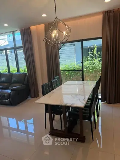 Spacious living room with elegant dining area and large windows offering natural light.