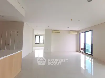 Spacious modern living room with large windows and balcony access in a bright apartment.