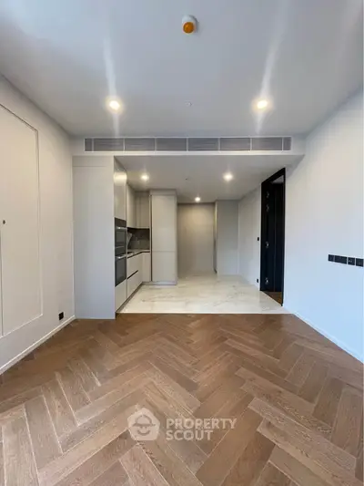 Modern open-plan living room with stylish herringbone flooring and sleek kitchen design.