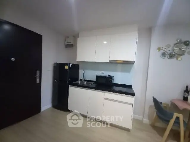 Modern kitchen with sleek cabinets and compact appliances in cozy apartment.