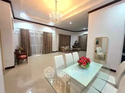 Elegant living and dining area with chandelier and glass table in spacious home