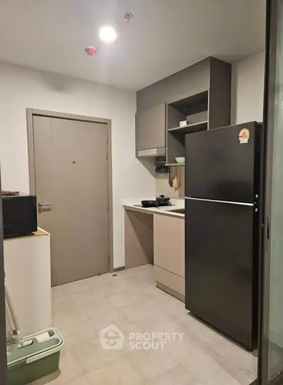 Modern compact kitchen with sleek cabinetry and stainless steel fridge in a cozy apartment.