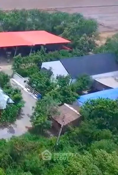 Aerial view of rural property with multiple buildings and lush greenery.