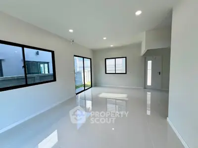 Spacious modern living room with large windows and glossy tiled floor