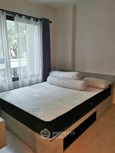 Cozy bedroom with large window and modern furnishings, perfect for relaxation and comfort.