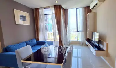 Modern living room with blue sofa, large windows, and sleek TV setup in a high-rise apartment.