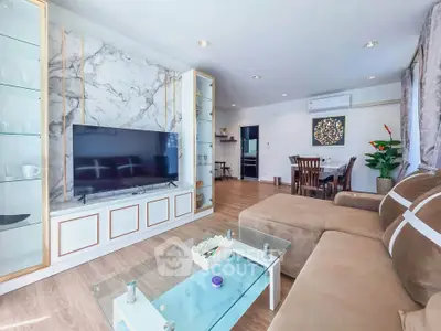 Spacious living room with modern decor and open layout, featuring a large TV and elegant dining area.