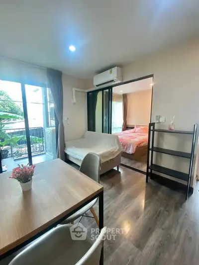 Modern apartment with open living area and bedroom, featuring balcony access and stylish decor.