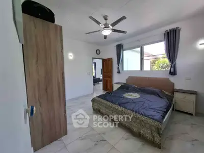 Spacious bedroom with modern ceiling fan and large window offering natural light.