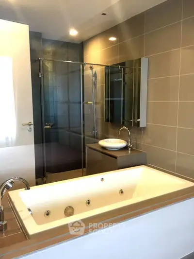 Luxurious modern bathroom with spacious bathtub and glass shower enclosure.