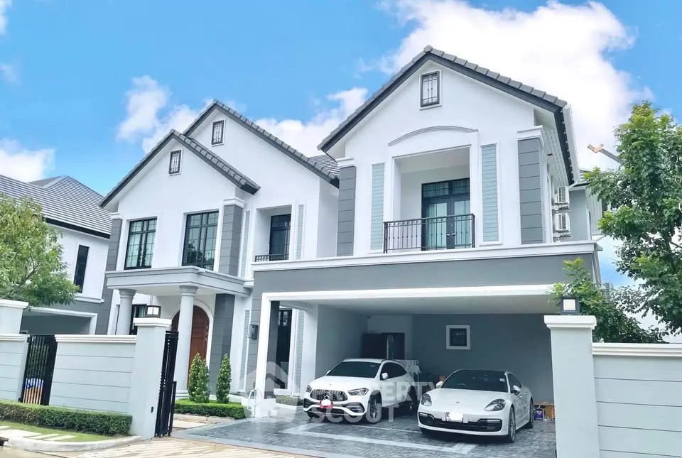 Luxurious modern house with spacious driveway and two cars parked, showcasing elegant architecture and lush greenery.