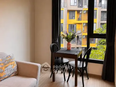 Cozy living room with modern decor and large window overlooking vibrant yellow building.