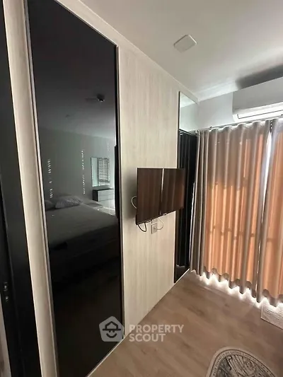 Modern bedroom with sleek design, featuring a wall-mounted TV and stylish curtains.