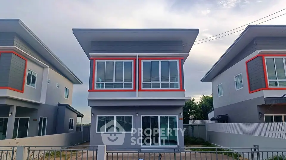 Modern two-story house with large windows and sleek design in suburban neighborhood.