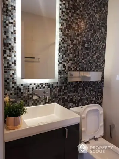 Modern bathroom with stylish mosaic tiles and illuminated mirror