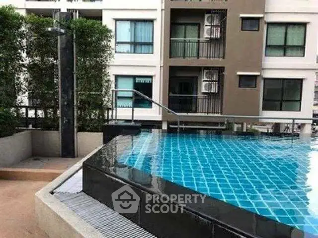 Modern apartment building with a stylish outdoor pool and lush greenery.