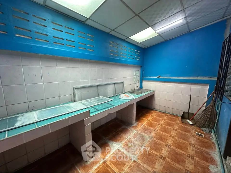 Spacious kitchen with tiled countertops and vibrant blue walls, ideal for culinary creativity.