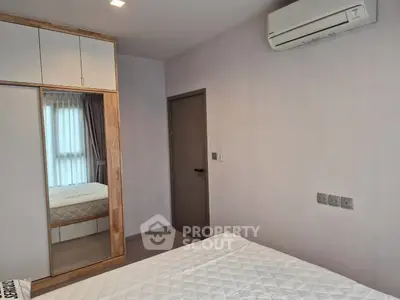 Modern bedroom with mirrored wardrobe and air conditioning in a stylish apartment.