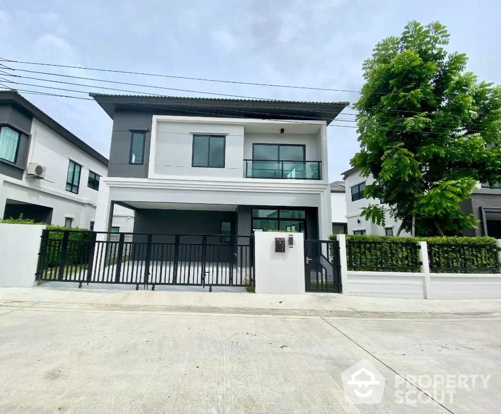 Modern two-story house with sleek design and spacious driveway in suburban neighborhood.