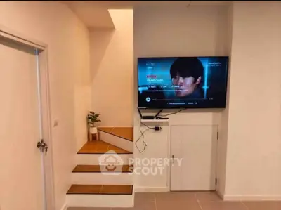 Modern interior with staircase and wall-mounted TV in cozy living space.