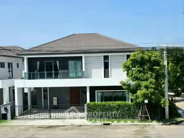 Modern two-story house with spacious balcony and lush greenery