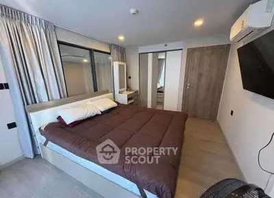 Modern bedroom with cozy bed, large mirror, and wall-mounted TV in stylish apartment.