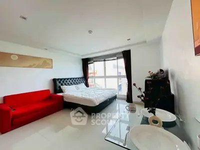 Spacious modern bedroom with red sofa and large window in stylish apartment.