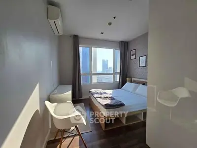 Bright and cozy bedroom with city view, modern furnishings, and ample natural light.